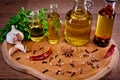 Close-up of bottles with olive oil with spices on a wooden background, cloves of garlic and parsley. Royalty Free Stock Photo