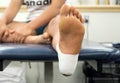 Close up bottom view of a female athlete`s foot in an ankle tape job from the bottom of a table