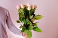 Close-up of bouquet of white, pink roses in hands of young man, brought flowers on date with girlfriend, gives to mom, concept of