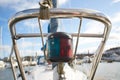 Close up of the bow of a sail boat in a marina, with lines, ropes and navigational lights in focus.