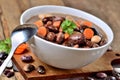 Close-up of bowl of bean soup with large beans , spoon, carrots, parsley and marjoram