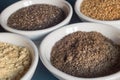 Close-up of a bowl with chia seeds powder along with other bowls of whole and powdered chia and flax seeds