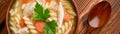 Close-up of a bowl of chicken noodle soup with spoon on a wooden background banner