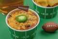 close up of bowl of chili with jalepeno pepper and football flag