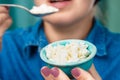 Close-up of a bowl of cottage cheese in the hands of a Caucasian woman. Focus on a bowl of cottage cheese