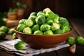 close up of bowl with fresh green Brussels sprouts on wooden background