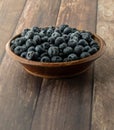 Close up of a bowl of frozen blueberries on a wooden table.