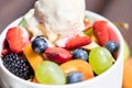 Close up of bowl with healthy fresh fruit salad with ice cream on wooden background Royalty Free Stock Photo