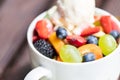 Close up of bowl with healthy fresh fruit salad with ice cream on wooden background Royalty Free Stock Photo