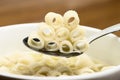 Close up of a bowl of macaroni soup. Spoon picking up macaroni,