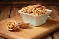 Close-up of a bowl of peeled walnut kernels on a wooden board. Studio shot