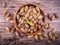 Close up of a bowl of pistachio nuts wood background