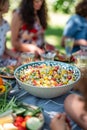 Close up of a bowl of salad on a picnic table with friends in the background Royalty Free Stock Photo