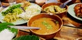 Close up bowl of spicy fish curry sauce on wooden table with Thai rice noodle, vegetable, grilled chicken and green curry Royalty Free Stock Photo