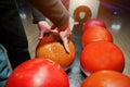 Close up of bowling player hand taking orange ball from bowl lif