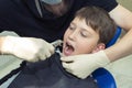 A close-up of a boy in a dental clinic. A doctor doing a procedure of pulling out a tooth with dental forceps Royalty Free Stock Photo