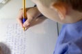 Close-up of boy hand with pencil writing english words by hand on traditional white notepad paper. Royalty Free Stock Photo