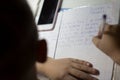 Close-up of boy hand with pencil writing english words by hand on traditional white notepad paper. Royalty Free Stock Photo