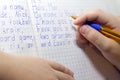 Close-up of boy hand with pencil writing english words by hand on traditional white notepad paper. Royalty Free Stock Photo