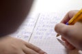 Close-up of boy hand with pencil writing english words by hand on traditional white notepad paper. Royalty Free Stock Photo