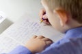 Close-up of boy hand with pencil writing english words by hand on traditional white notepad paper. Royalty Free Stock Photo