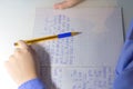 Close-up of boy hand with pencil writing english words by hand on traditional white notepad paper. Royalty Free Stock Photo