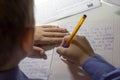 Close-up of boy hand with pencil writing english words by hand on traditional white notepad paper. Royalty Free Stock Photo