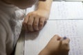 Close-up of boy hand with pencil writing english words by hand on traditional white notepad paper. Royalty Free Stock Photo