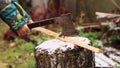 Close-up of a boy`s hand clumsily chopping a stick with an ax.