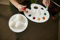 Close-up of a boy`s hand squeezing green paint from a tube onto a palette for coloring Easter eggs Royalty Free Stock Photo