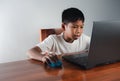 Close up The boy sits staring at the laptop and his hand is holding the mouse. educational concept, educational information search