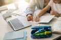 Close up of boy sitting at table and writing in copybook on online lesson while his mom helping him Royalty Free Stock Photo