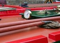 aclose up of a brass gauge porthole boathooks and ropes on an old red canal narrow boat