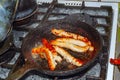 Close up,Breakfast for all ages,Pigs in Blankets or Mini sausages wrapped in smoked bacon on a hot frying pan on a charcoal grill Royalty Free Stock Photo