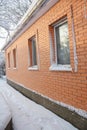 Close up on brick house wall facade and window sill covered snow outdoor. Royalty Free Stock Photo