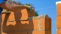 CLOSE UP: Bricklayer places a brick on top of wet concrete while building a wall Royalty Free Stock Photo