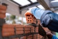 Close up of Bricklayer worker installing brick masonry on exterior wall with trowel putty knife on construction site