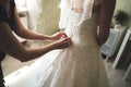 Close up of bridal corset. Rear view on bride in white wedding dress. Bridesmaid helping bride to dress wedding gown Royalty Free Stock Photo