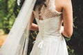 Close up of bridal corset. Rear view on bride in white wedding gown with laces. Outdoor photo. Wedding day concept. Royalty Free Stock Photo