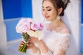 A close-up of the bride breathes in the scent of pink and white peonies. The girl in a wedding dress with a bouquet of