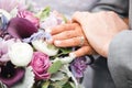 Close up of bride and groom hands with wedding rings on bridal bouquet with roses, peonies and lilies Royalty Free Stock Photo