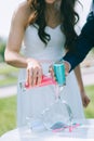 Close up of bride and groom pouring colorful sand into a glass vase in the shape of a heart. Royalty Free Stock Photo