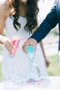 Close up of bride and groom pouring colorful sand into a glass vase in the shape of a heart Royalty Free Stock Photo