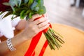 Close-up of bride hands holding beautiful wedding bouquet with red and pink roses. Concept of floristics and jewellery. Royalty Free Stock Photo