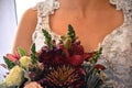 Close up of bride`s chest white beaded ornate dress with jewel colored flower bouquet Royalty Free Stock Photo