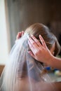 Close up bride straightens her hair with a veil, back view