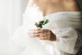 Close-up of the bride& x27;s hands holds a boutonniere. Woman in a beautiful white dress. Bride& x27;s preparations. Wedding