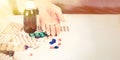 Close-up of bright colored medical pills and capsules with medications and a Woman`s hand next to them. Pills from the