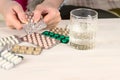 Close-up of bright colored medical pills and capsules with medicines in a woman`s hand and a glass of water next to them. The Royalty Free Stock Photo