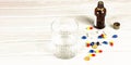 Close-up of bright colored medical tablets, a bottle of medicine and capsules with medicines and a glass of water. Scattered on